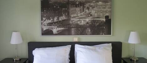 A hotel room with a bed, two nightstands, and a large black and white cityscape painting on the wall.