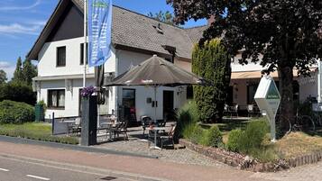 Een hotel met terras, een vlag en een bord met de naam van het hotel.