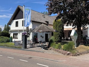 Een hotel met terras, een vlag en een bord met de naam van het hotel.