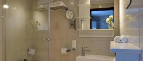 A modern bathroom with a glass shower enclosure, a bathtub, a toilet, and a vanity with a mirror and towel rack.