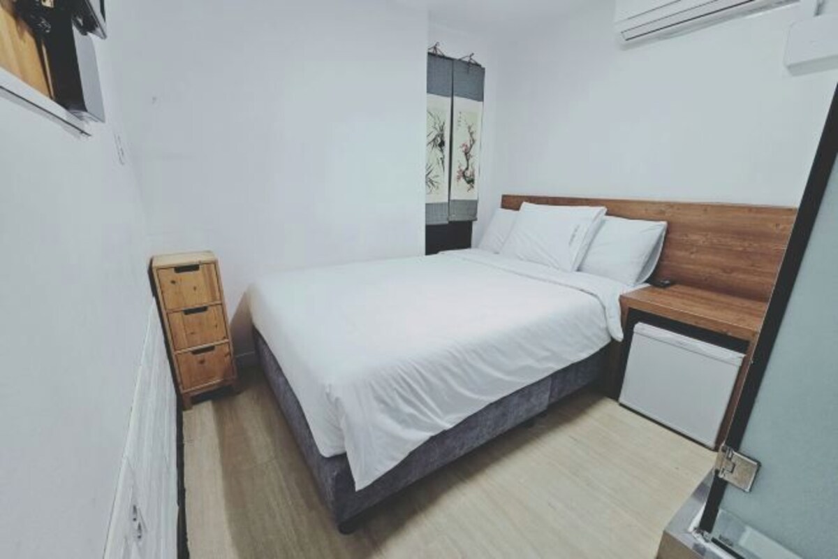 A small, neatly arranged bedroom with a bed, bedside table, and a small cabinet.