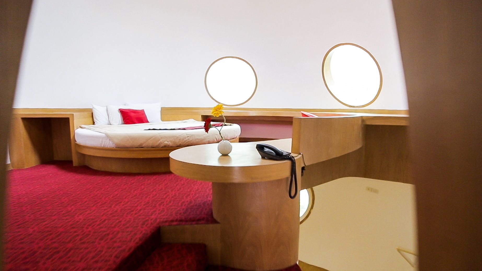 Una habitación de hotel pequeña con una cama, un escritorio, una silla y un tocador con espejos.