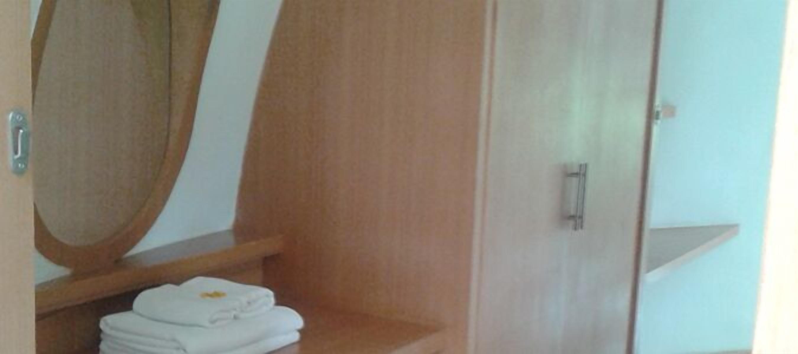 A bathroom with a wooden vanity, a mirror, and a towel rack with folded towels.