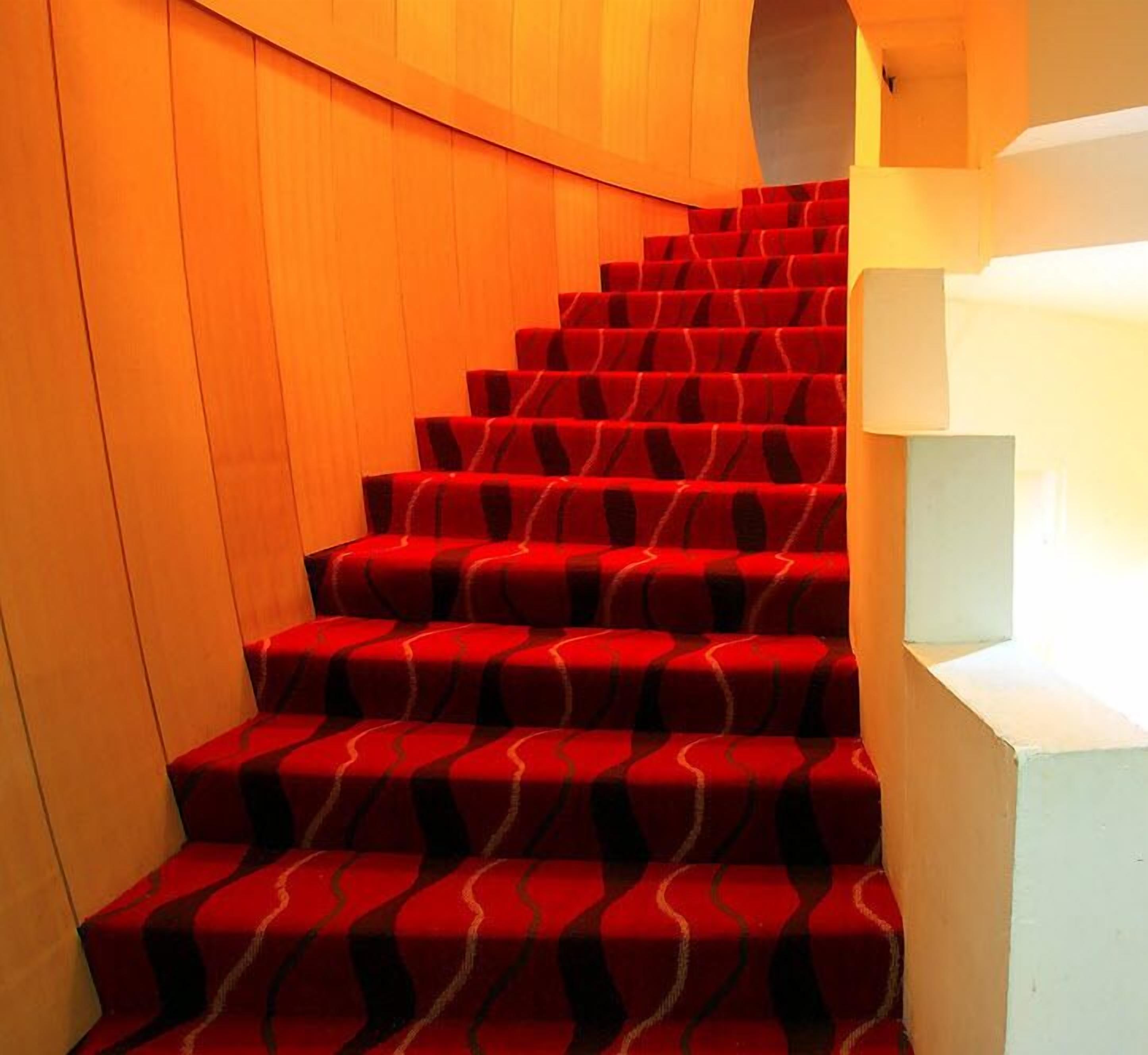 A staircase with red carpeted steps and white walls.