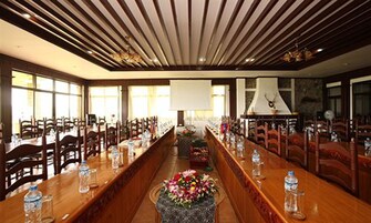 Un salón de conferencias con largas mesas, sillas y una pantalla grande al frente.