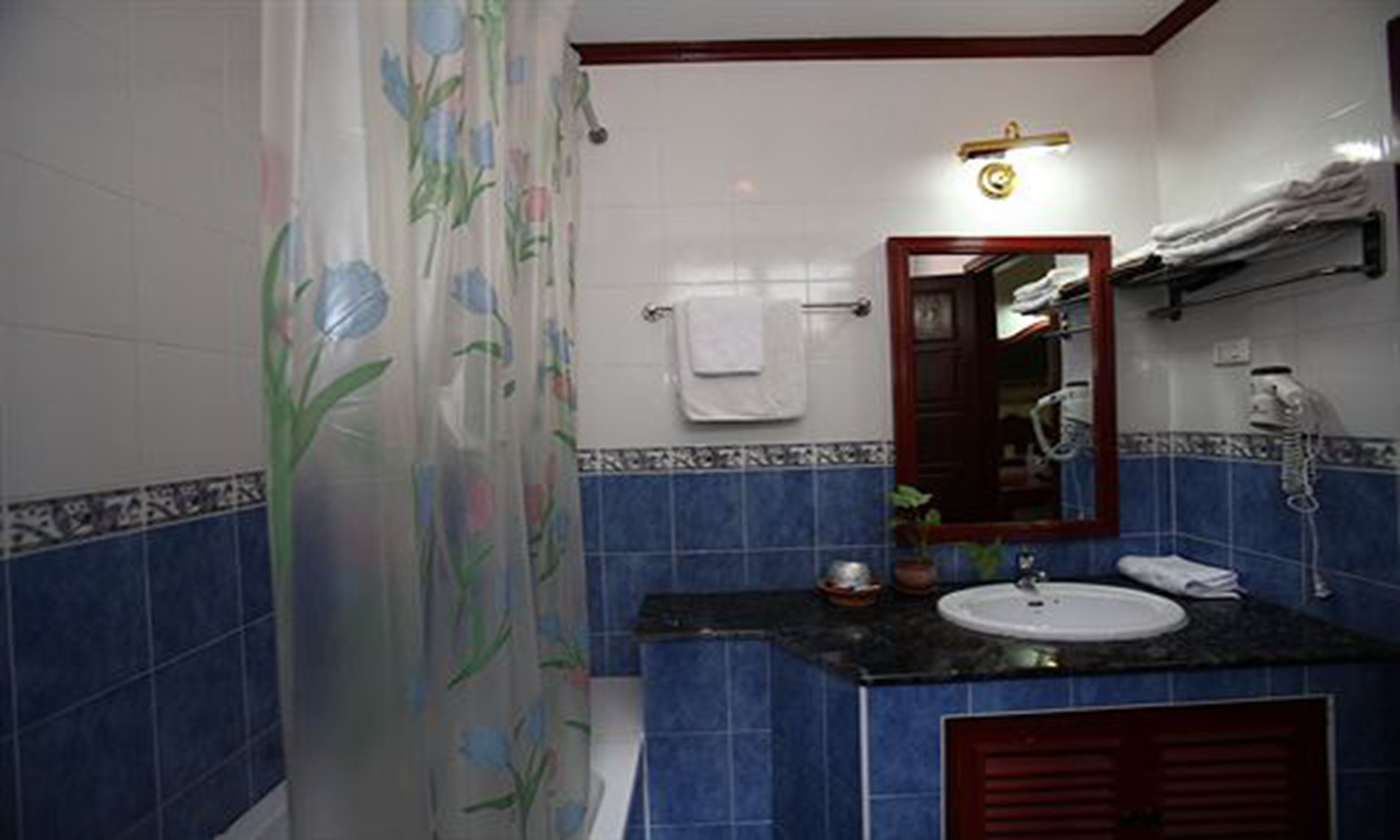 A bathroom with a shower curtain, a sink, a mirror, and a towel rack.