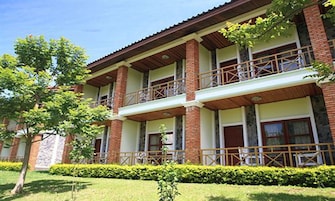 Un edificio de varios pisos con fachada de ladrillo, balcones y un césped bien cuidado.