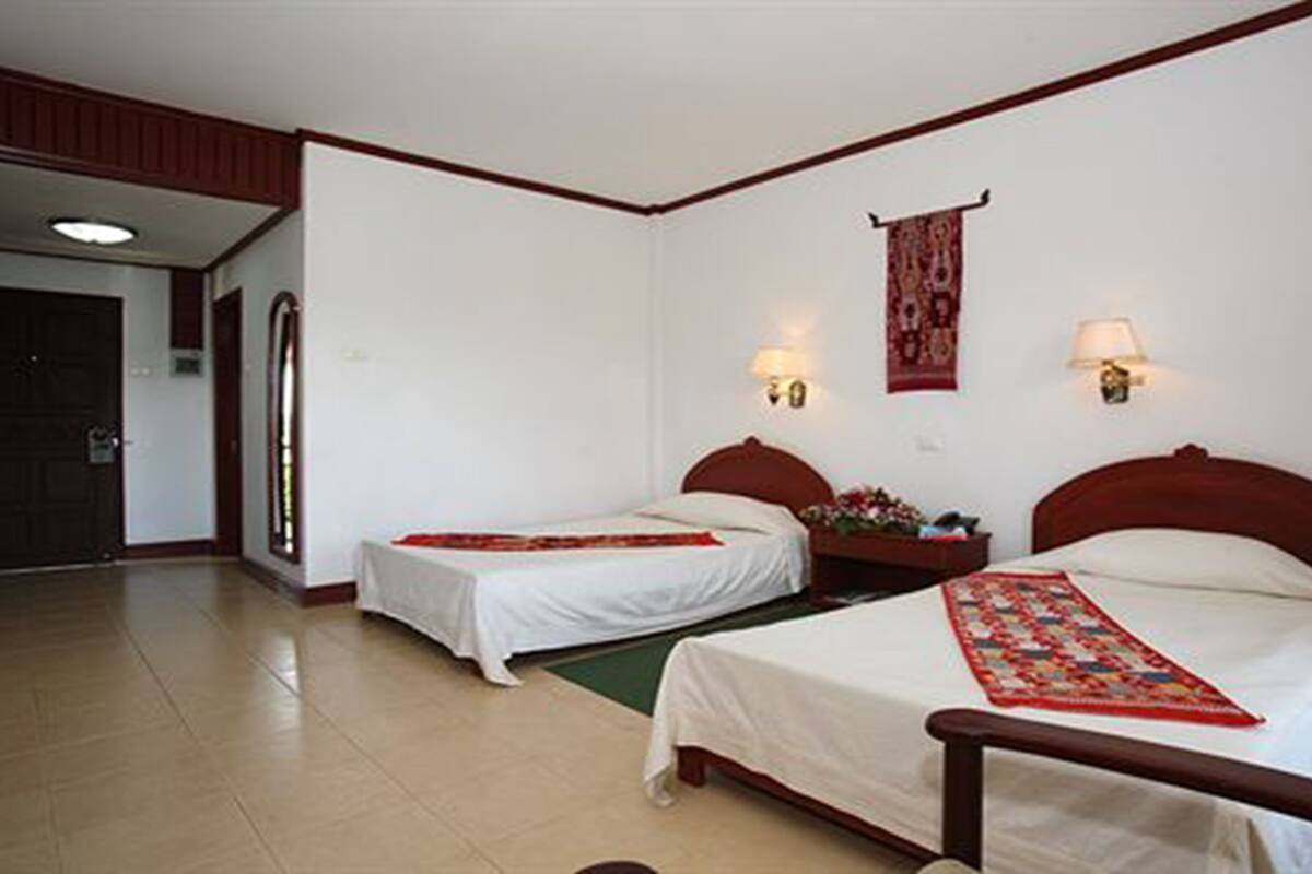 Habitación de hotel con dos camas, una mesita y una silla.