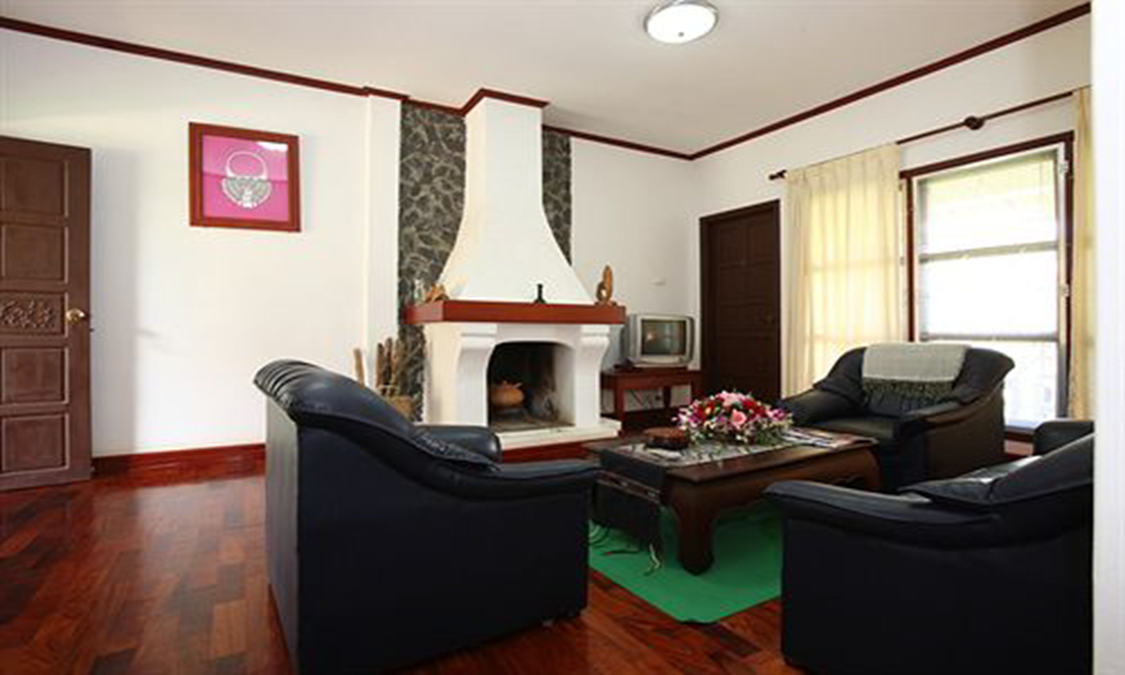 Un salon avec deux canapés en cuir noir, une table basse en bois, une cheminée et un téléviseur posé sur un meuble en bois.