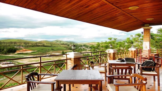 Eine Holzterrasse mit Tischen und Stühlen mit Blick auf eine malerische Landschaft.