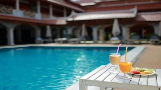A poolside setting with a table, drinks, and fruit.
