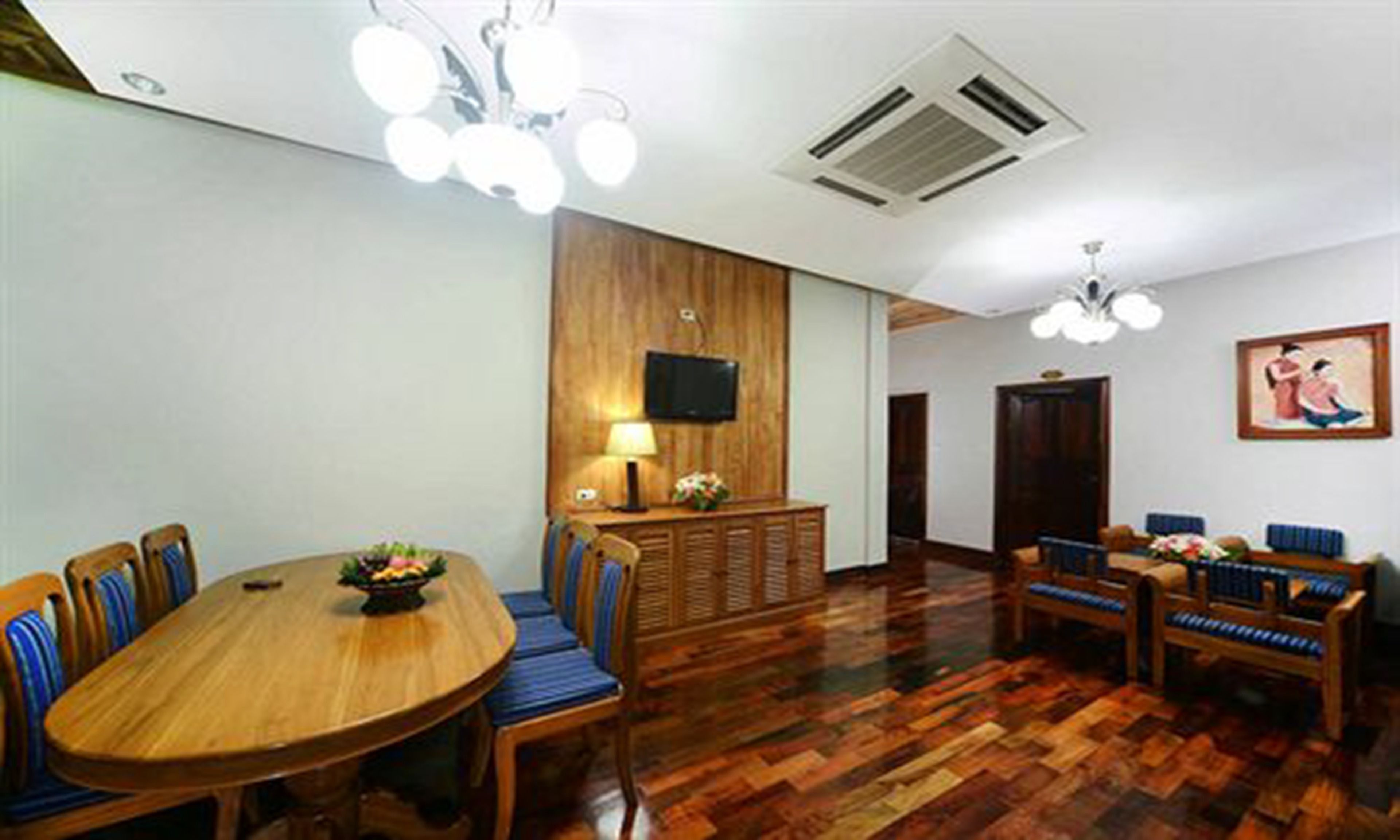 A conference room with a wooden table and chairs, a television on the wall, and a patterned floor.