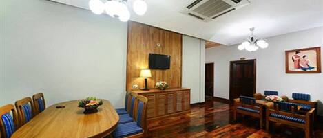 A conference room with a wooden table and chairs, a television on the wall, and a patterned floor.