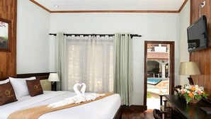 A hotel room with a bed, a desk, a chair, a TV, and a window with curtains.