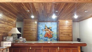 A reception desk with a wooden finish, a framed artwork above it, and a 'TIP-BOX' sign on the left.