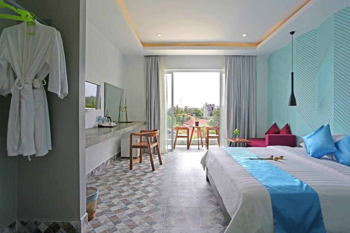 Una habitación de hotel con cama, escritorio, silla, mesa y balcón con vistas.