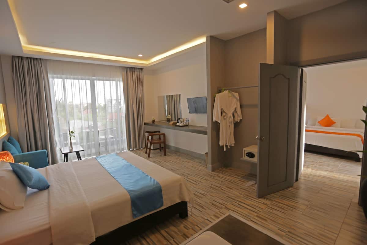 Una habitación de hotel moderna con una cama grande, un escritorio, un baño con bañera y vistas a la ciudad a través de amplios ventanales.