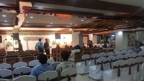 A conference room with rows of chairs, some with white covers and brown sashes. - Hotel TARA International (Hyderabad)