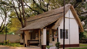 A small, single-story building with a thatched roof and a white exterior. - Pamusha Lodge (Victoria Falls)