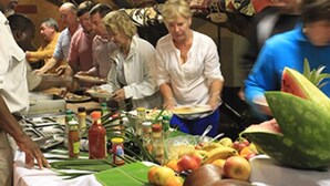 A group of people at a buffet with various fruits and condiments on the table. - Pamusha Lodge (Victoria Falls)