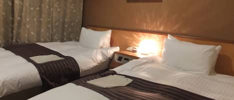 A hotel room with two beds, a nightstand with a lamp, and a painting on the wall.