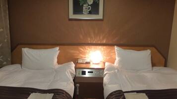A hotel room with two beds, a nightstand with a lamp, and a framed picture on the wall.