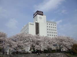 A multi-story building with a clock tower, a sign reading "City Hotel," and a large number of windows.