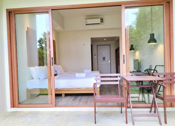 A bedroom with a bed, a wooden bench, and a table with chairs. - Nest Sense Resort (Ko Chang)