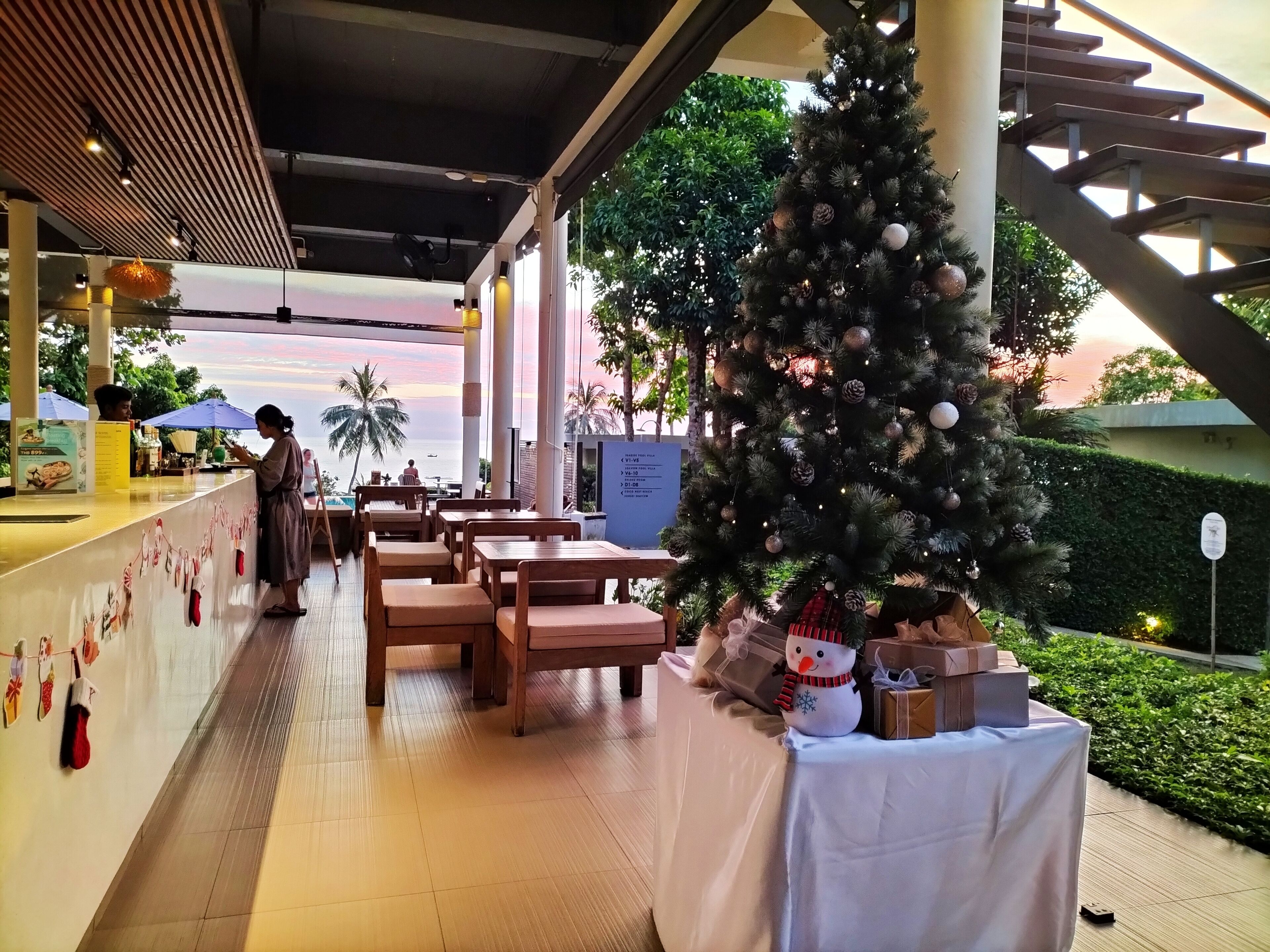 A restaurant with a Christmas tree and gifts, overlooking a scenic view.