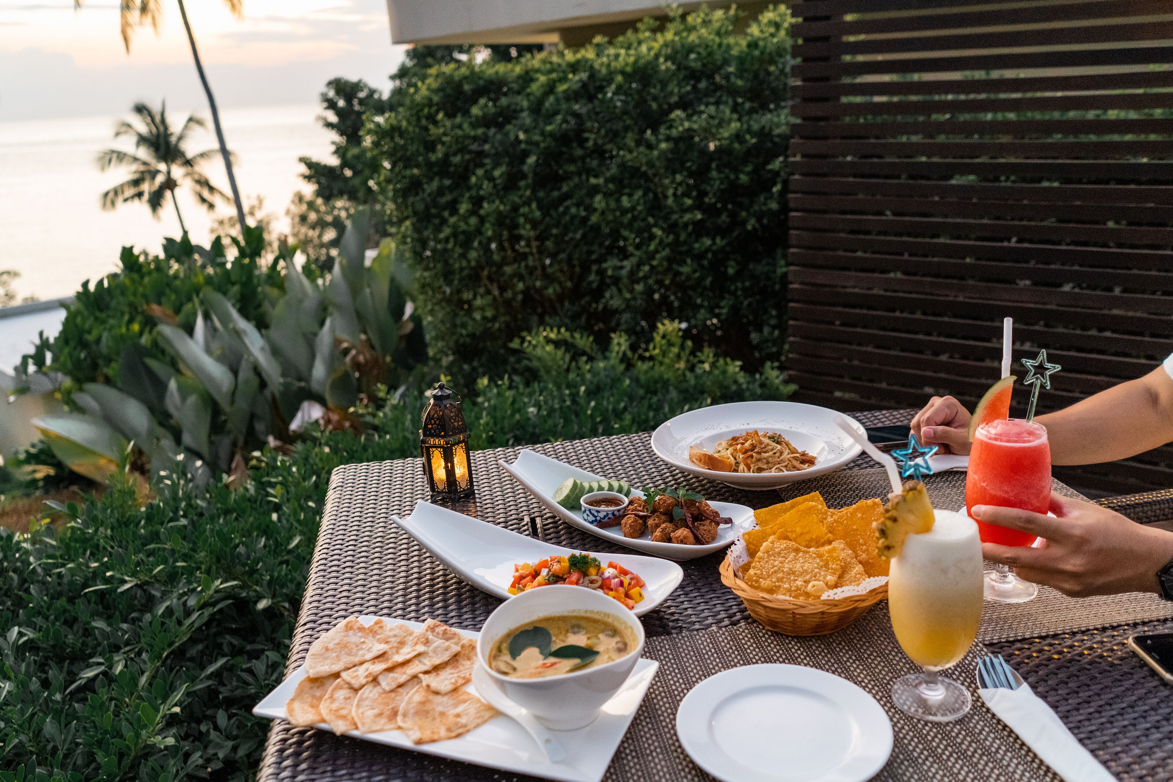 Una mesa colocada al aire libre con diversos platos, una bebida y un teléfono inteligente.