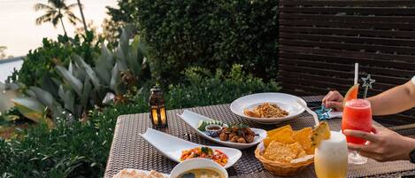 Una mesa colocada al aire libre con diversos platos, una bebida y un teléfono inteligente.