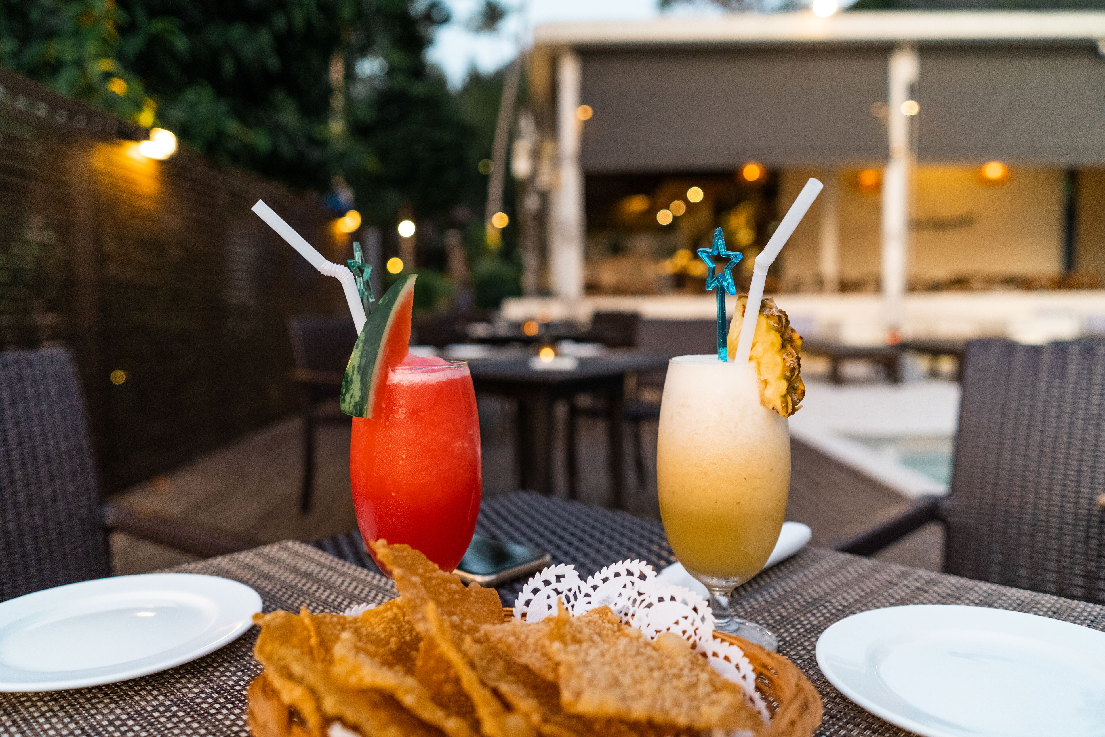 A table with two drinks, a plate of chips, and a white napkin.