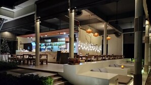 Un espace de détente intérieur moderne, avec un bar en arrière-plan et un escalier menant à un niveau supérieur.