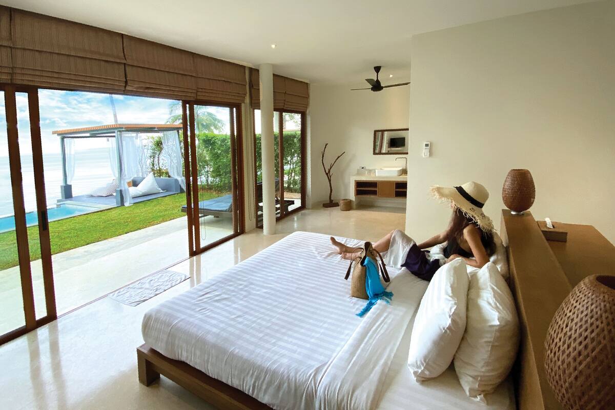 A spacious bedroom with a large bed, a view of a pool, and a modern bathroom.