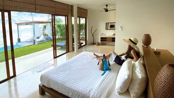 Un dormitorio amplio con una cama grande, vista a una piscina y un baño moderno.