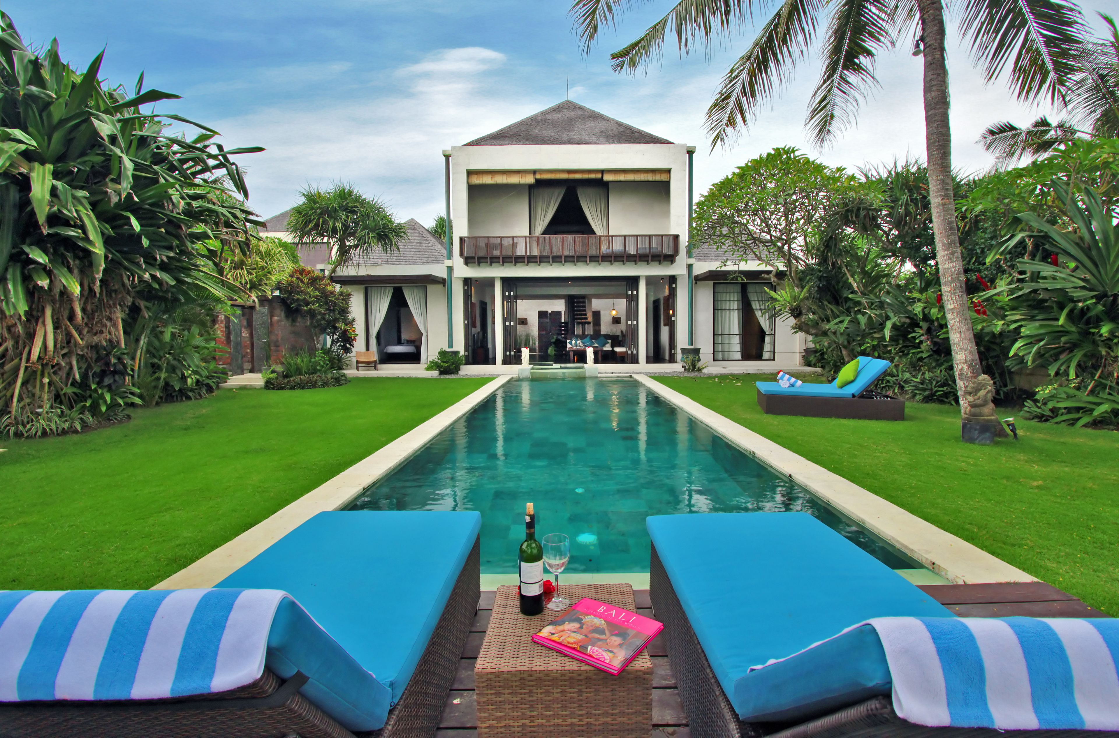 A poolside view with lounge chairs, a book, and a bottle.