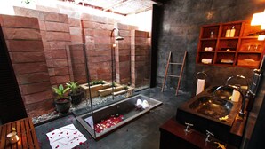 Un baño moderno con ducha de vidrio, un banco de madera y un lavabo con espejo.