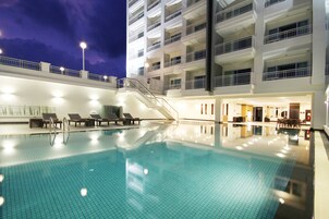 Una piscina al aire libre, sillones reclinables de piscina