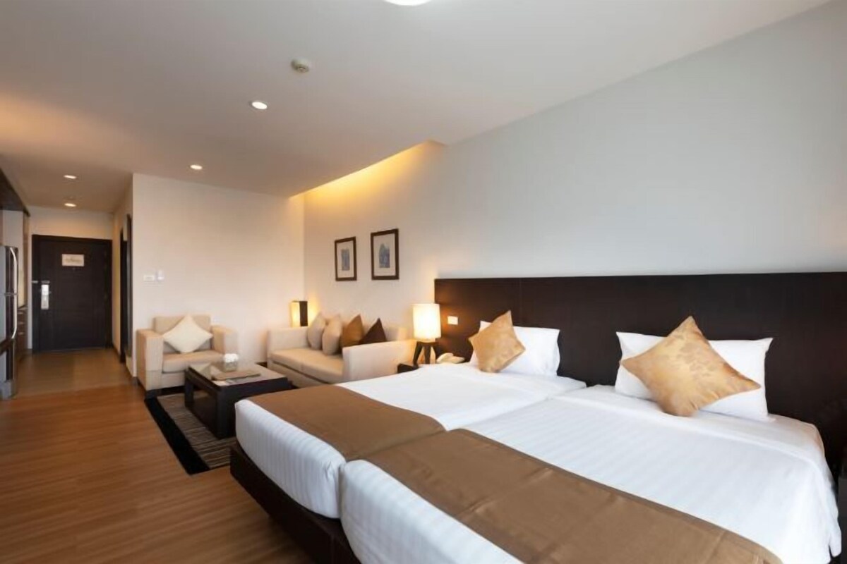 Una habitación de hotel con dos camas, un sofá, un escritorio y una mesita de noche.