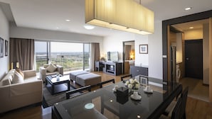 Una habitación de hotel moderna con balcón, zona de comedor, sala de estar y kitchenette.