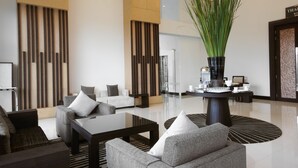 Un lobby moderno con zona de estar, una mesa de centro y una planta decorativa.