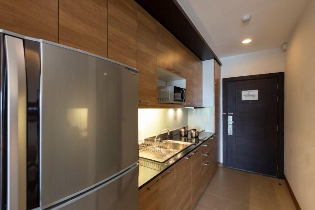 Una cocina moderna con electrodomésticos de acero inoxidable, armarios de madera y una puerta oscura.