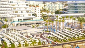 A resort with multiple levels of buildings, outdoor seating areas, and a beach with sun loungers. - Vrissiana Boutique Beach Hotel (Paralimni)
