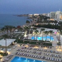 Un resort con una piscina grande, tumbonas y palmeras.