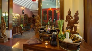 A massage parlor with wooden furniture, statues, and a display of massage oils and herbs.
