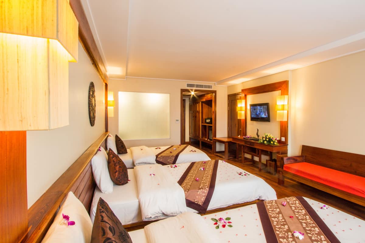 Habitación de hotel con una cama grande, un escritorio, un televisor y un banco rojo.