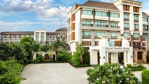 A hotel with a prominent entrance, multiple floors, and a well-maintained garden area.