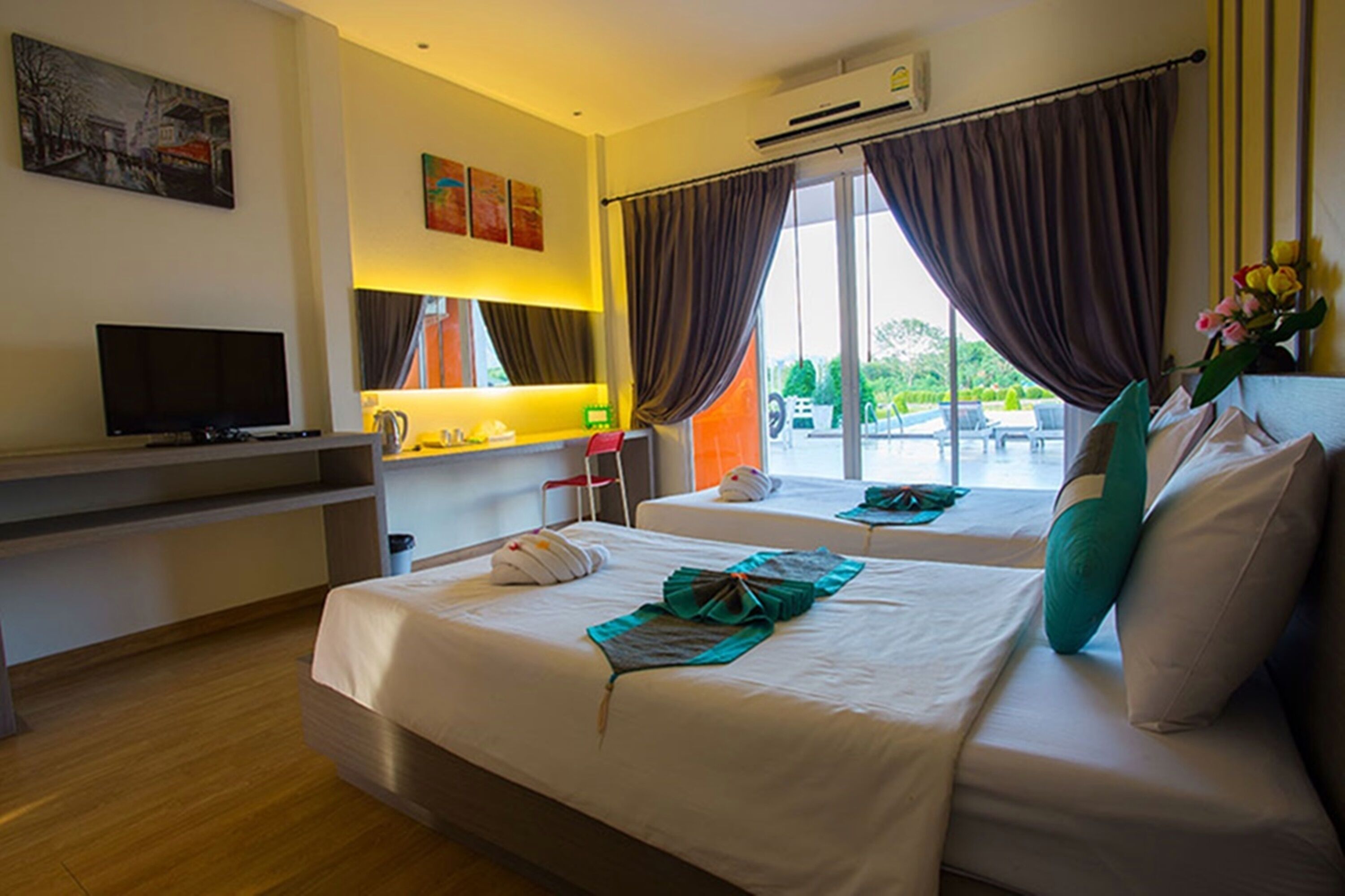 A hotel room with two beds, a TV, a desk, and a window with curtains.