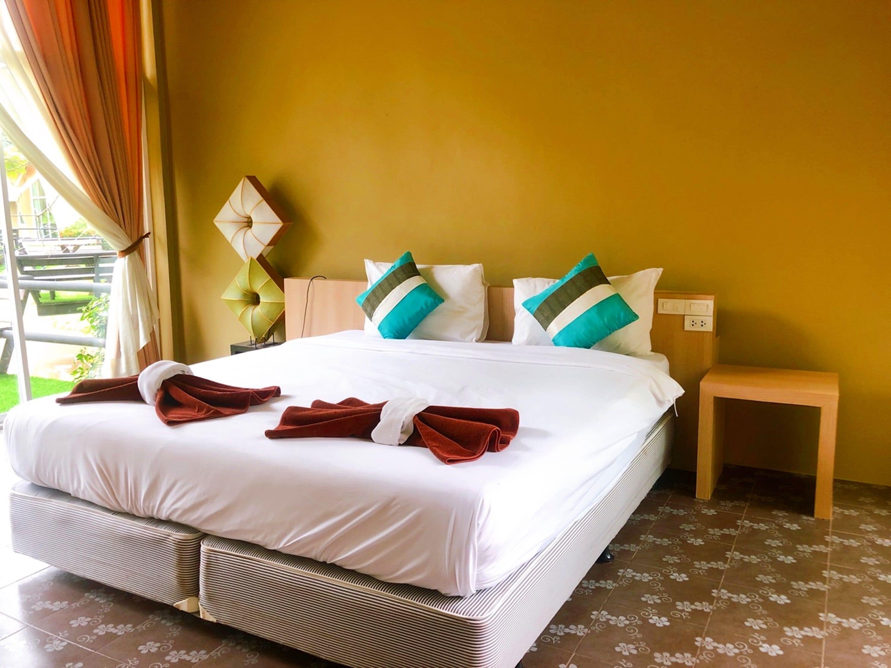 Una habitación de hotel con una cama grande, una mesita de noche y vistas al exterior.