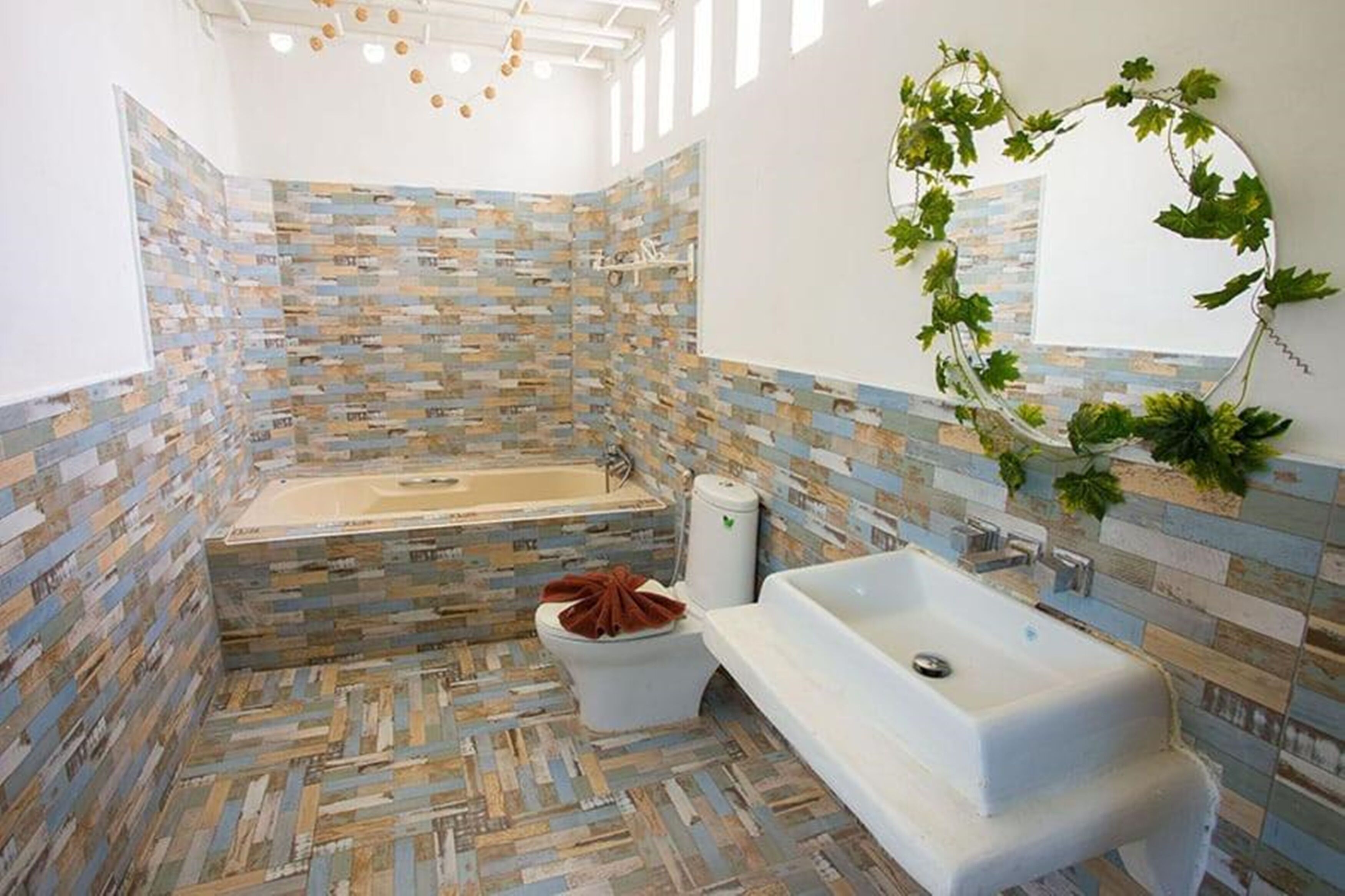 A bathroom with a mosaic tile wall, a freestanding bathtub, a sink, and a toilet.